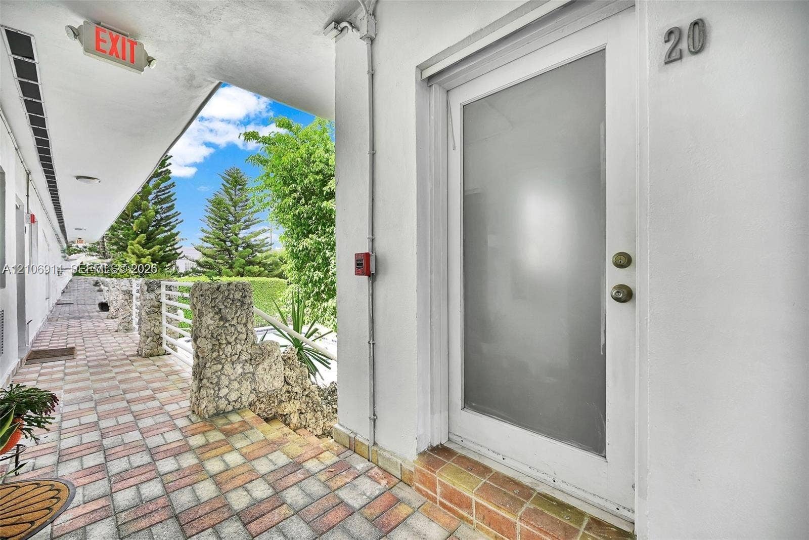 320 85th Street, #20, Miami Beach, Miami Beach, FL 33141 Exterior entrance featuring a frosted glass door, concrete block walkway, natural stone pillar accents, and a covered walkway
