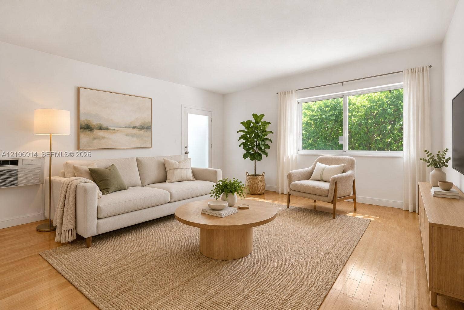 320 85th Street, #20, Miami Beach, Miami Beach, FL 33141 Living space staged featuring wood-finish flooring, a large horizontal window with natural light, and a dedicated wall-mounted air conditioning unit