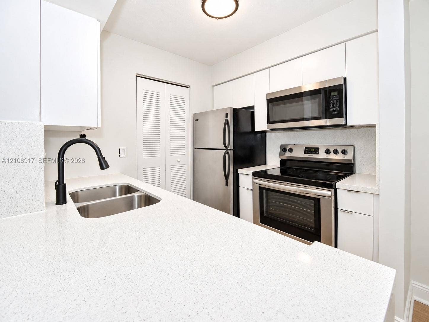 Kitchen featuring white flat-panel cabinetry, stone-finish countertops, stainless steel appliances, and a matte black gooseneck faucet