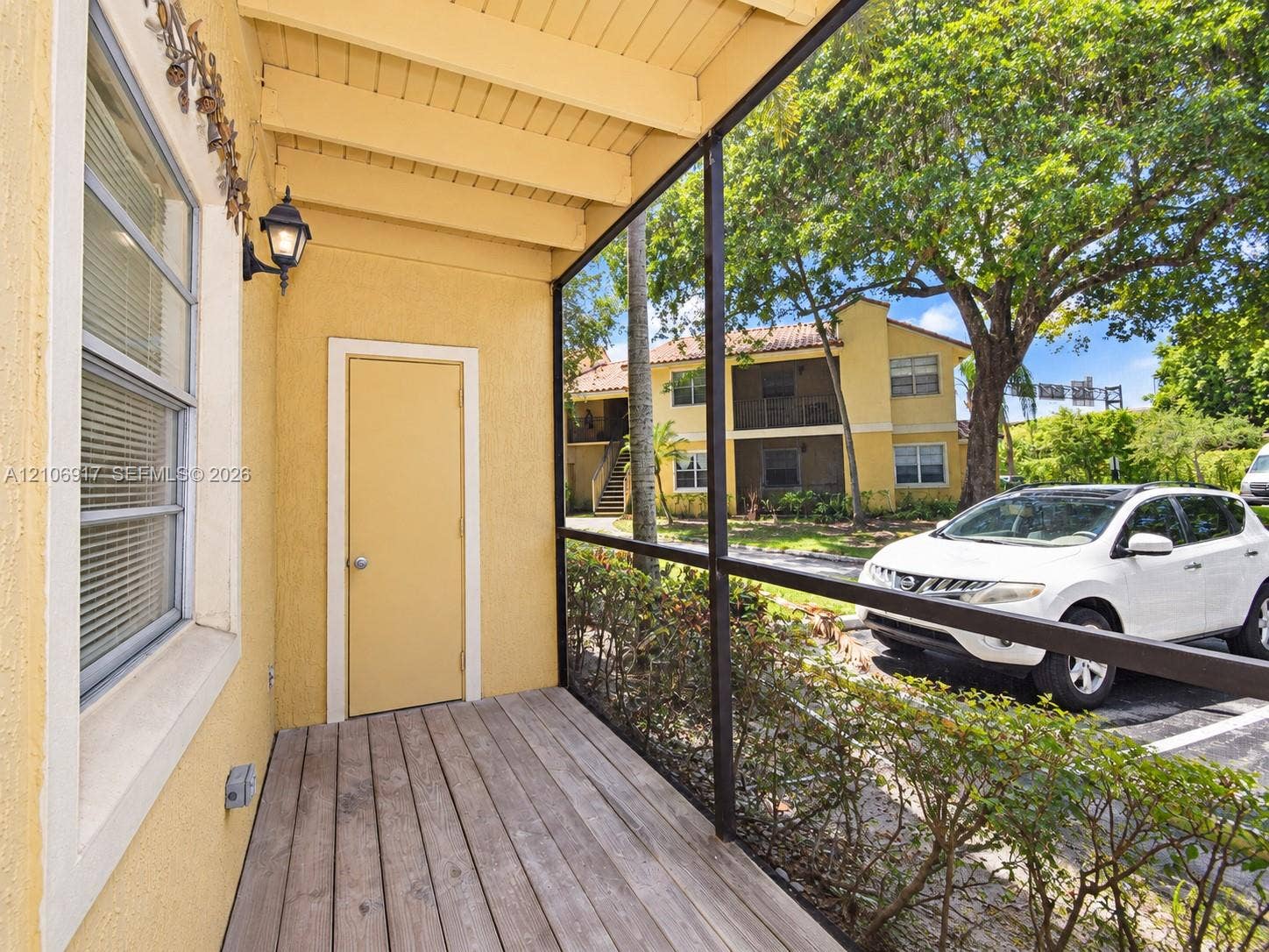 Screened porch featuring a wood-plank floor, stucco exterior walls, and wall-mounted exterior lighting