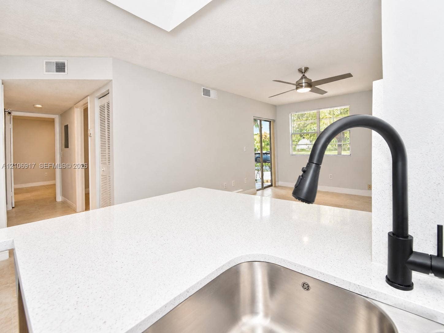 Kitchen island featuring a white stone countertop, undermount stainless steel sink, and matte black gooseneck faucet