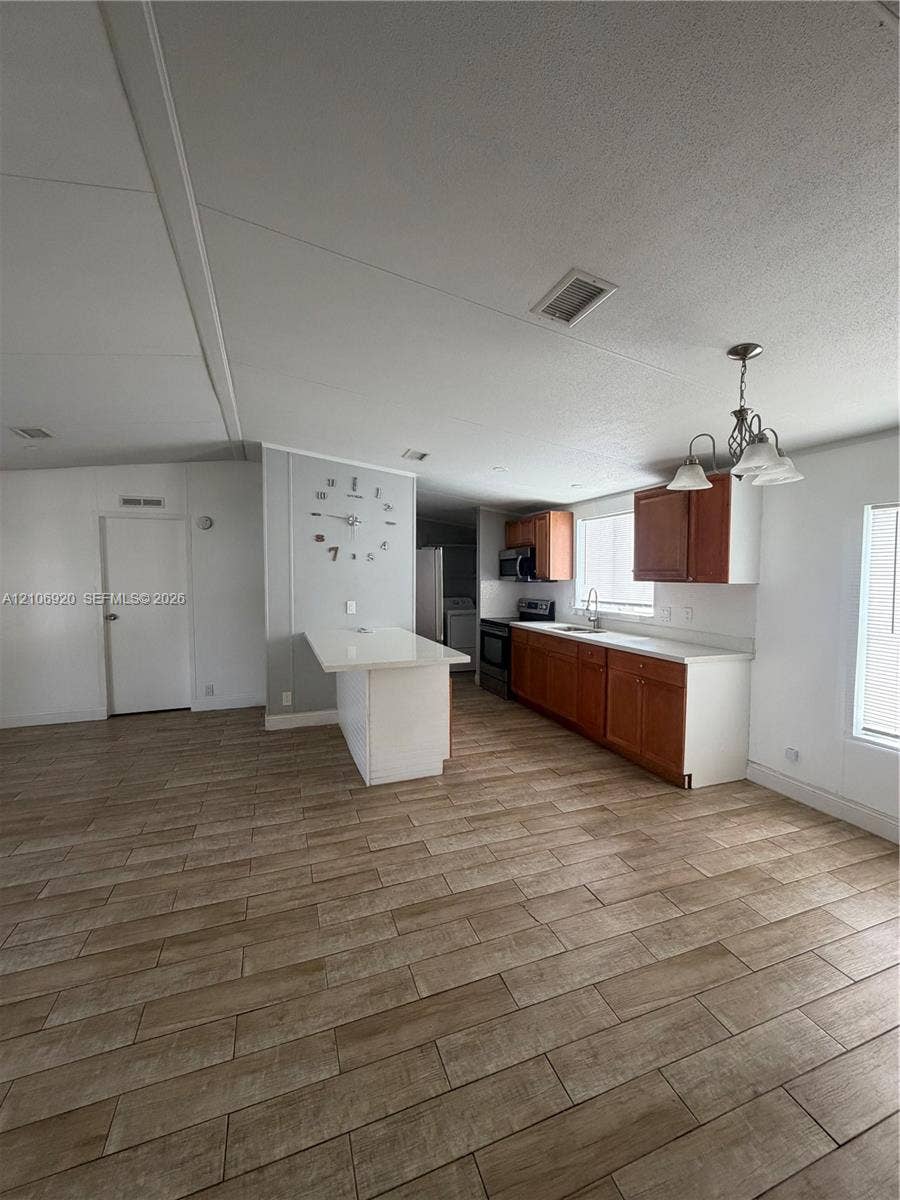 19800 SW 180 Avenue, #t, Miami, FL 33187 Kitchen featuring wood-finish cabinetry, white countertops, a center island, wood-finish flooring, and a multi-light chandelier