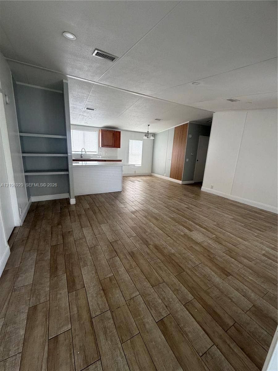 19800 SW 180 Avenue, #t, Miami, FL 33187 Open-concept interior featuring wood-finish flooring, built-in shelving, kitchen peninsula, recessed lighting, and wooden cabinetry