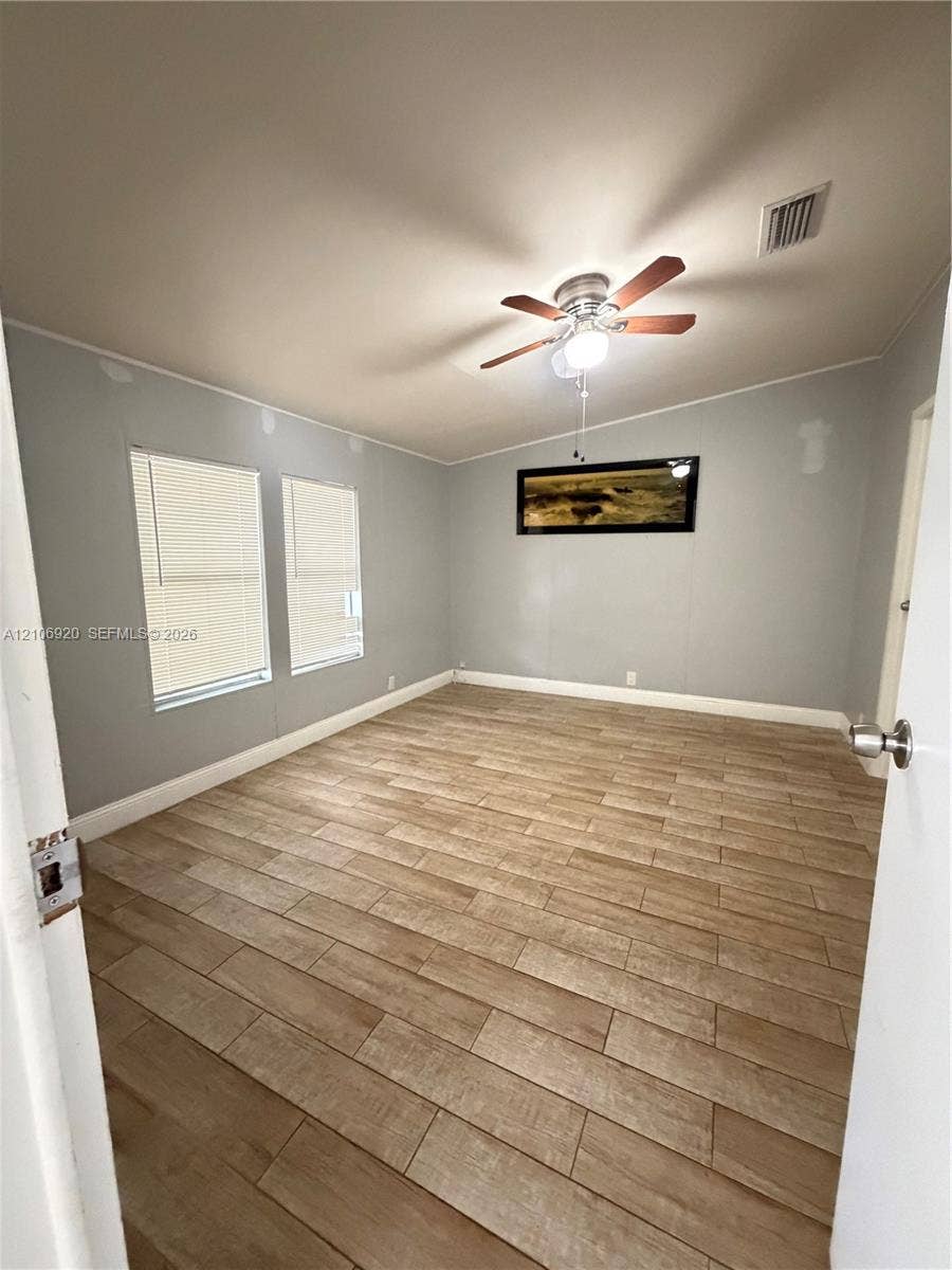 19800 SW 180 Avenue, #t, Miami, FL 33187 Interior room featuring wood-finish flooring, two windows with integrated blinds, and a ceiling-mounted light fixture with a fan