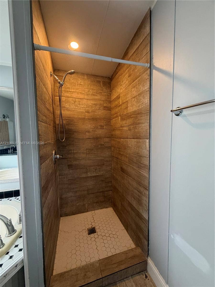 19800 SW 180 Avenue, #t, Miami, FL 33187 Walk-in shower featuring wood-finish tile surround, white hexagonal floor tile, chrome handheld shower head, and recessed lighting