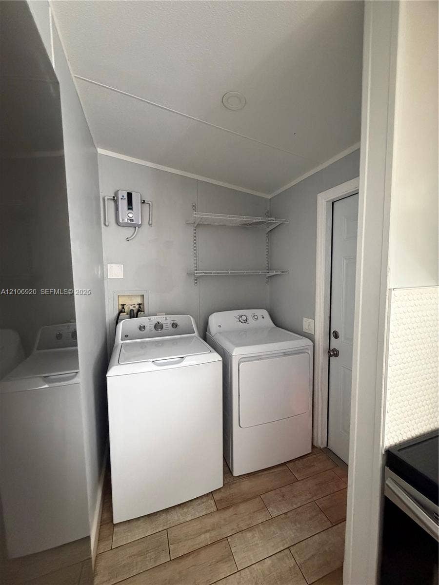19800 SW 180 Avenue, #t, Miami, FL 33187 Dedicated laundry area featuring wood-finish flooring, two-tier wall-mounted shelving, and plumbing hookups
