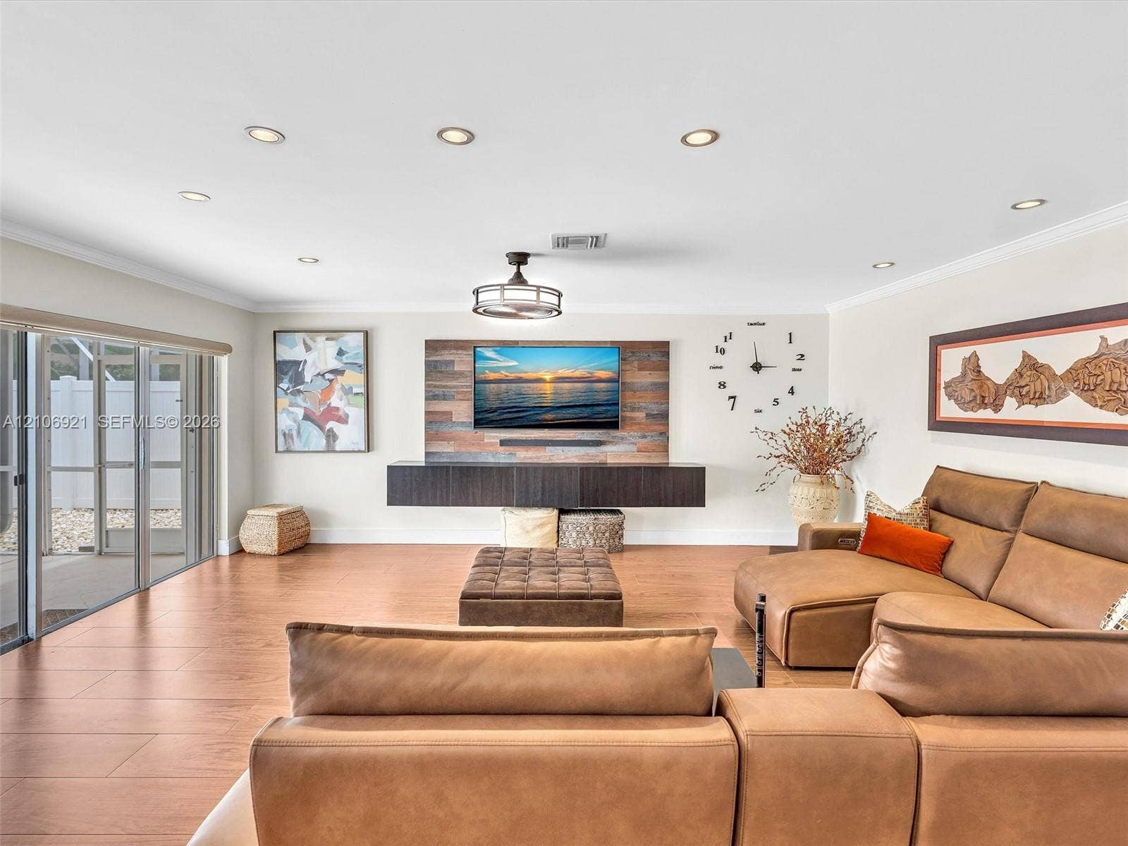 Open-concept living space featuring wood-finish flooring, recessed lighting, a floating media console, and a reclaimed wood-style accent wall