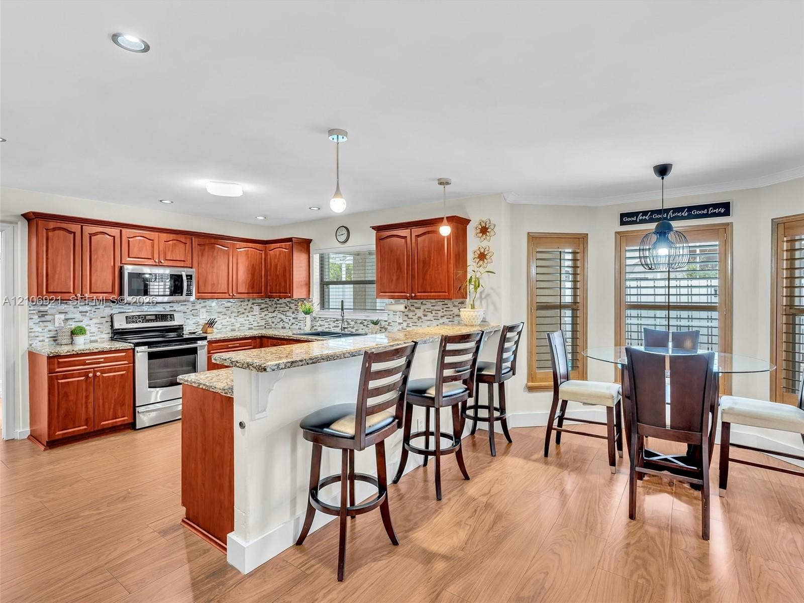 Kitchen featuring stained wood cabinetry, stone-finish countertops, stainless steel appliances, decorative stone backsplash, and wood-finish flooring