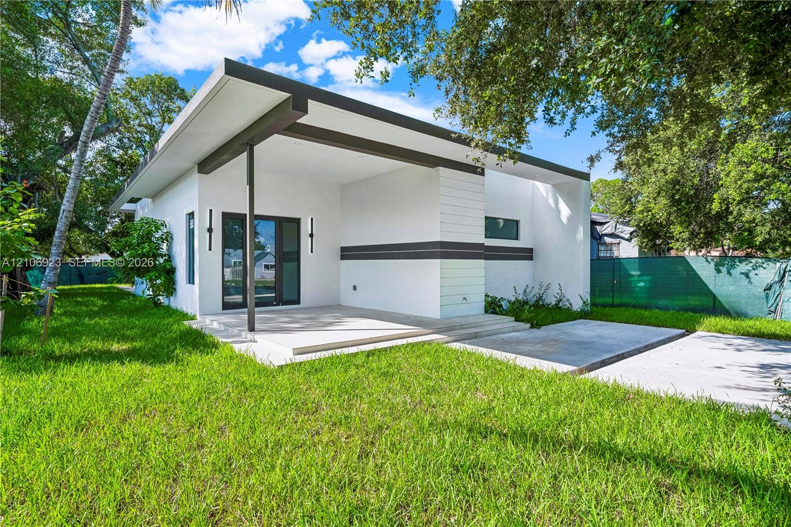 870 Superior Street, Opa Locka, FL 33054 Modern exterior featuring a flat roofline, integrated covered patio, horizontal siding accents, and concrete hardscaping