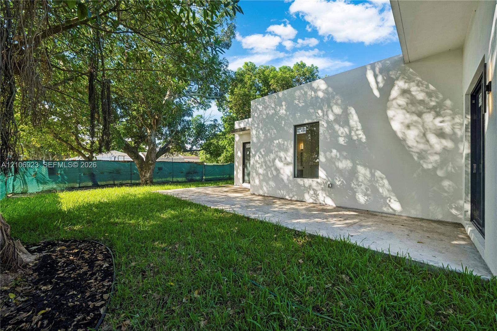 870 Superior Street, Opa Locka, FL 33054 Backyard featuring a paved patio, manicured lawn, mature trees, and an exterior light fixture