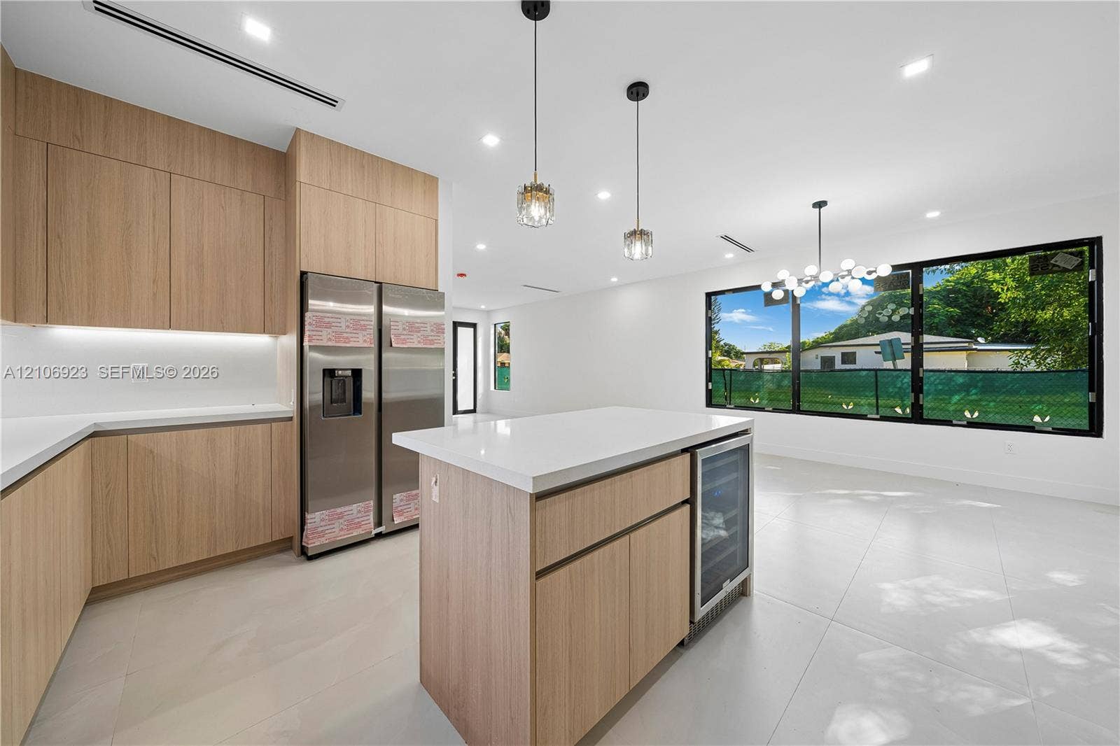 870 Superior Street, Opa Locka, FL 33054 Kitchen featuring wood-finish flat-panel cabinetry, quartz countertops, a central island with an integrated wine cooler, stainless steel refrigerator, and large picture windows
