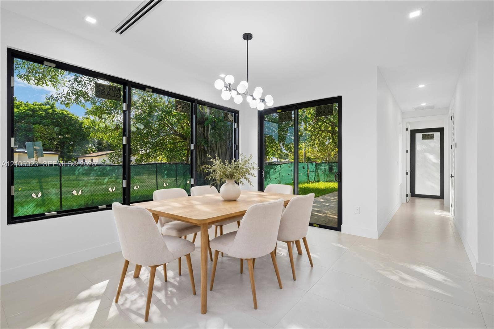 870 Superior Street, Opa Locka, FL 33054 Dining area featuring expansive floor-to-ceiling black-framed windows, integrated recessed lighting, a modern multi-globe chandelier, and porcelain tile flooring