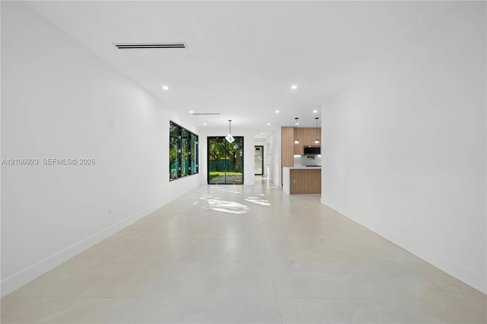 870 Superior Street, Opa Locka, FL 33054 Open floor plan featuring large-format tile flooring, recessed lighting, expansive glass sliding doors, and a kitchen equipped with natural wood-finish cabinetry