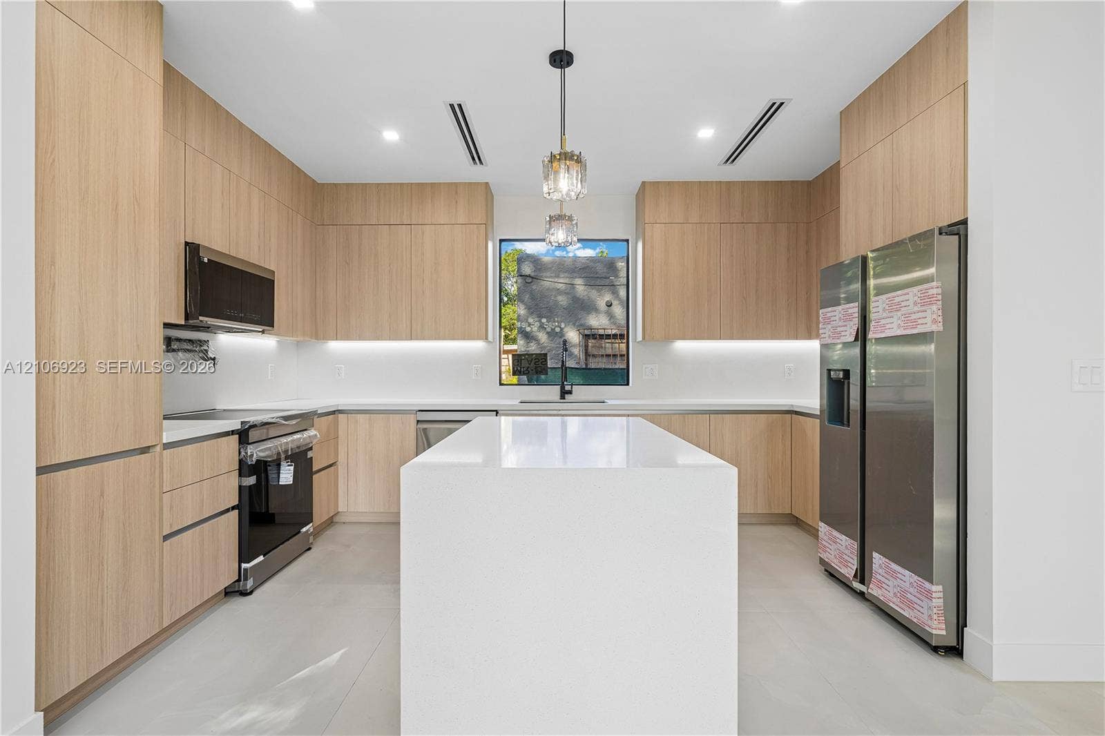 870 Superior Street, Opa Locka, FL 33054 Modern kitchen featuring flat-panel wood-finish cabinetry, a large quartz-topped island, stainless steel appliances, under-cabinet lighting, and recessed ceiling lighting