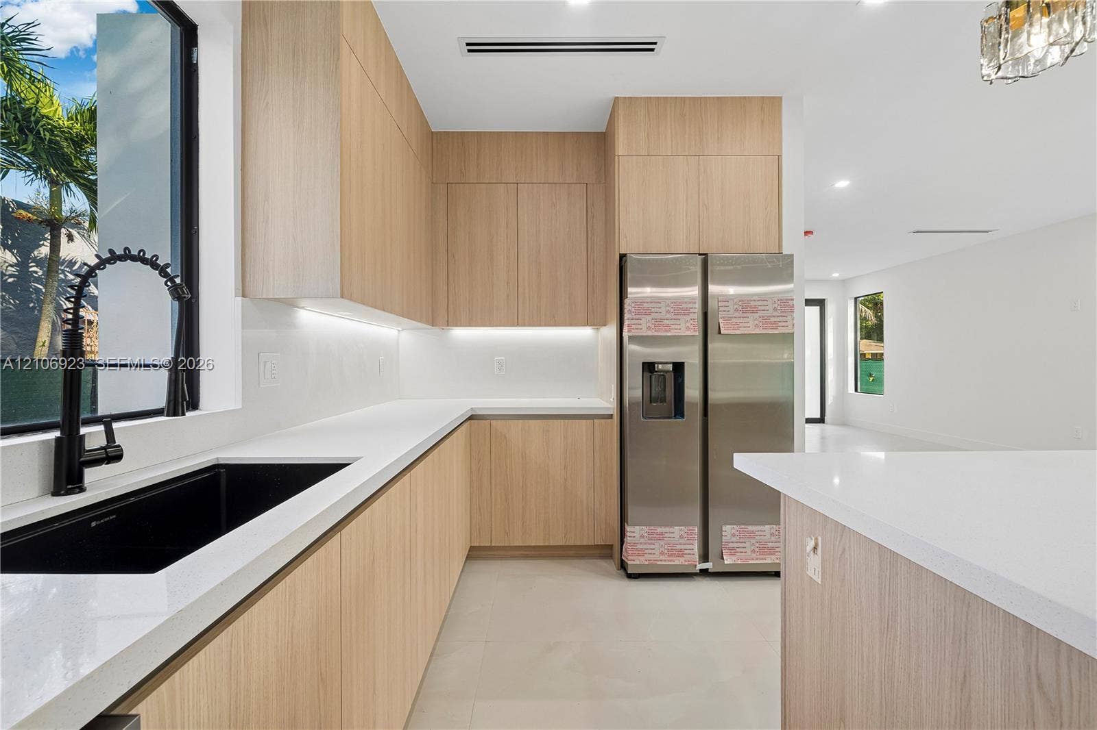 870 Superior Street, Opa Locka, FL 33054 Kitchen featuring flat-panel wood-finish cabinetry, white countertops, black undermount sink with high-arc faucet, stainless steel refrigerator, and recessed lighting