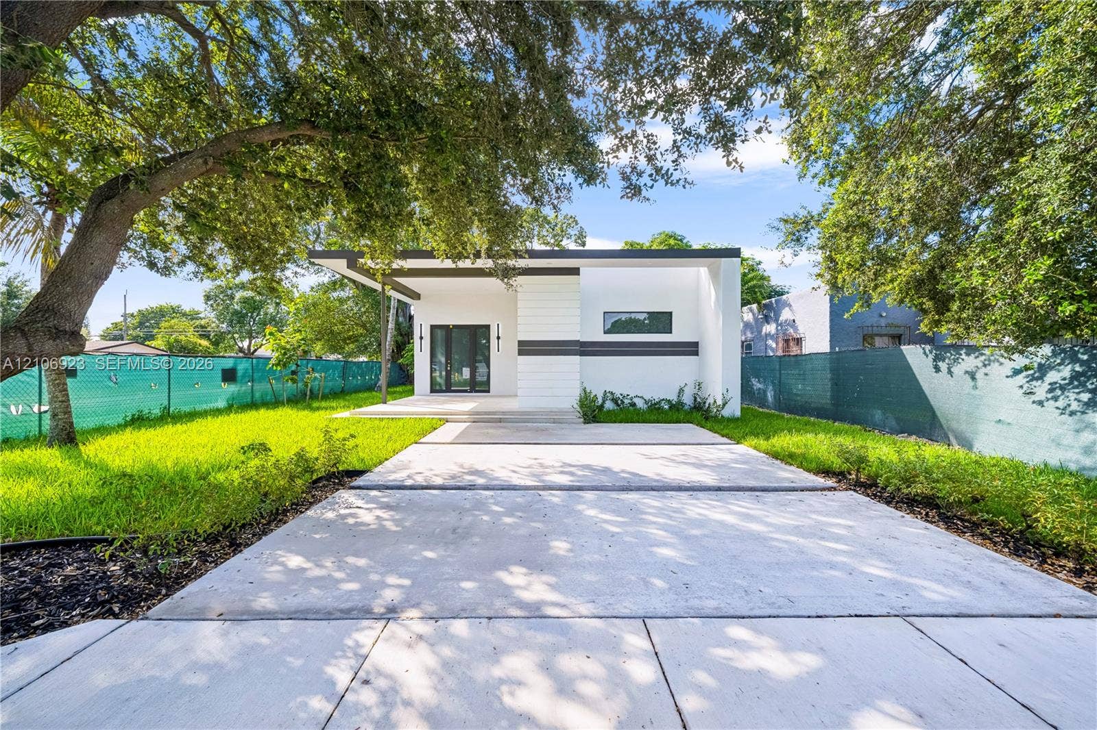 870 Superior Street, Opa Locka, FL 33054 Modern exterior featuring clean lines, a flat roofline, minimalist facade detailing, a paved concrete driveway, and mature landscaping