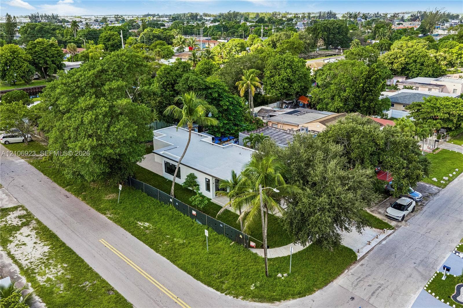 870 Superior Street, Opa Locka, FL 33054 Single-story residence featuring a flat roofline, corner lot placement, mature landscaping, palm trees, and an asphalt driveway