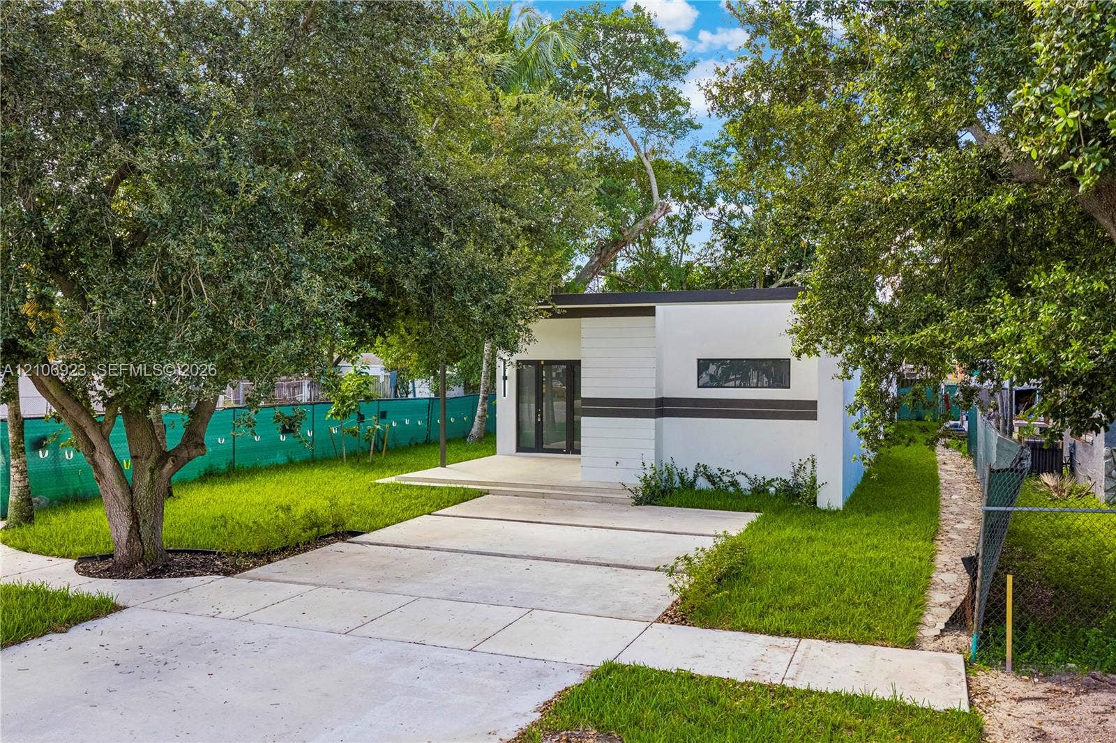 870 Superior Street, Opa Locka, FL 33054 Modern minimalist exterior featuring a crisp white finish with linear accent detailing, concrete driveway, and a covered entry