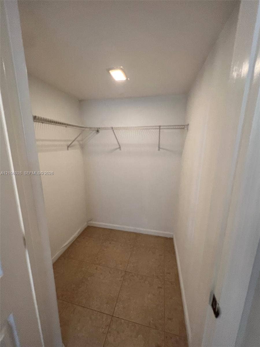 Walk-in closet featuring ceramic tile flooring, built-in wire shelving, and flush-mount overhead lighting
