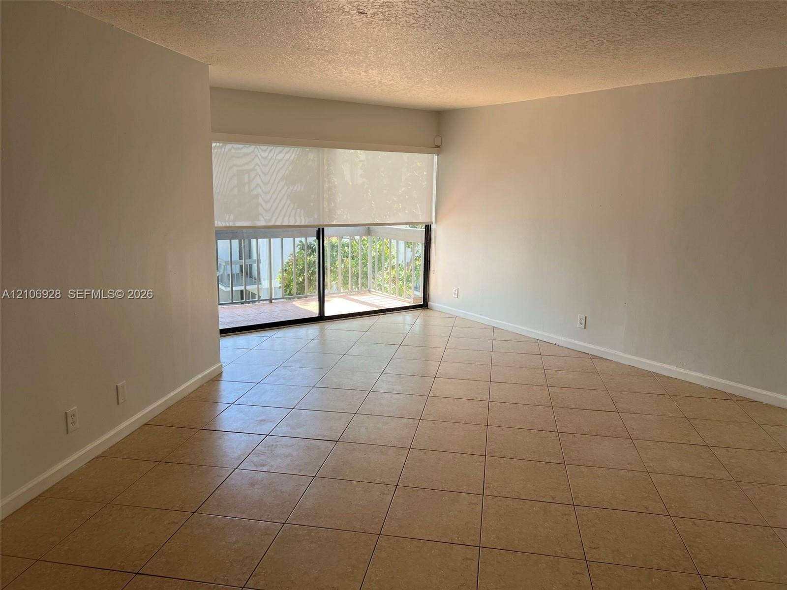 Open-concept area featuring oversized ceramic tile flooring, neutral wall tones, sliding glass doors, and a private balcony