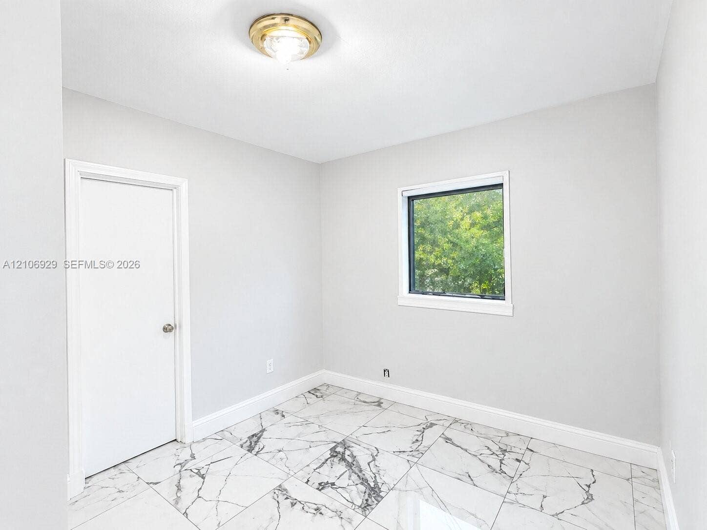 12700 Wood Street, Miami, FL 33167 Neutral-toned interior featuring large-format tile flooring with a veined finish, a single-pane window, and a flush-mount circular ceiling fixture