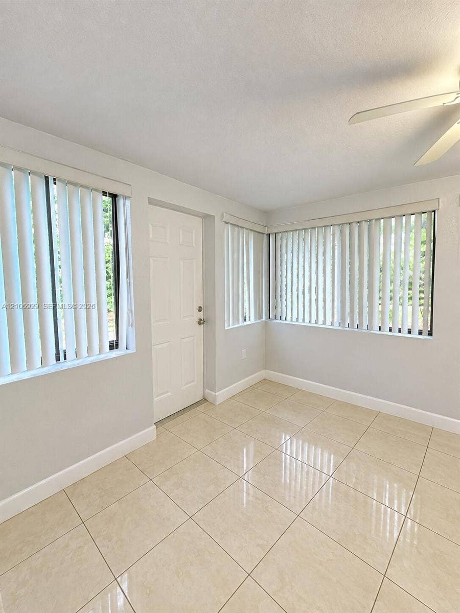 12700 Wood Street, Miami, FL 33167 Neutral-toned tile flooring, multiple windows with vertical blinds, and a ceiling fan