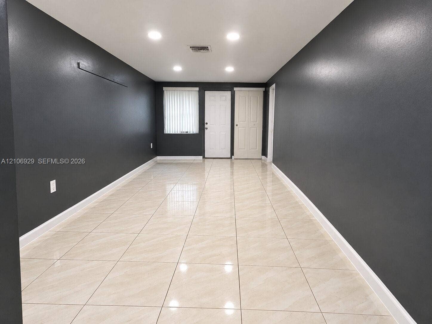 12700 Wood Street, Miami, FL 33167 Interior space featuring large-format neutral tile flooring, recessed ceiling lighting, and dark-toned wall finishes