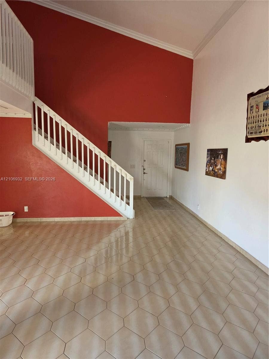 6328 NW 181st Terrace, Hialeah, FL 33015 Foyer featuring high vaulted ceilings, hexagonal ceramic tile flooring, and a staircase with a white wooden railing