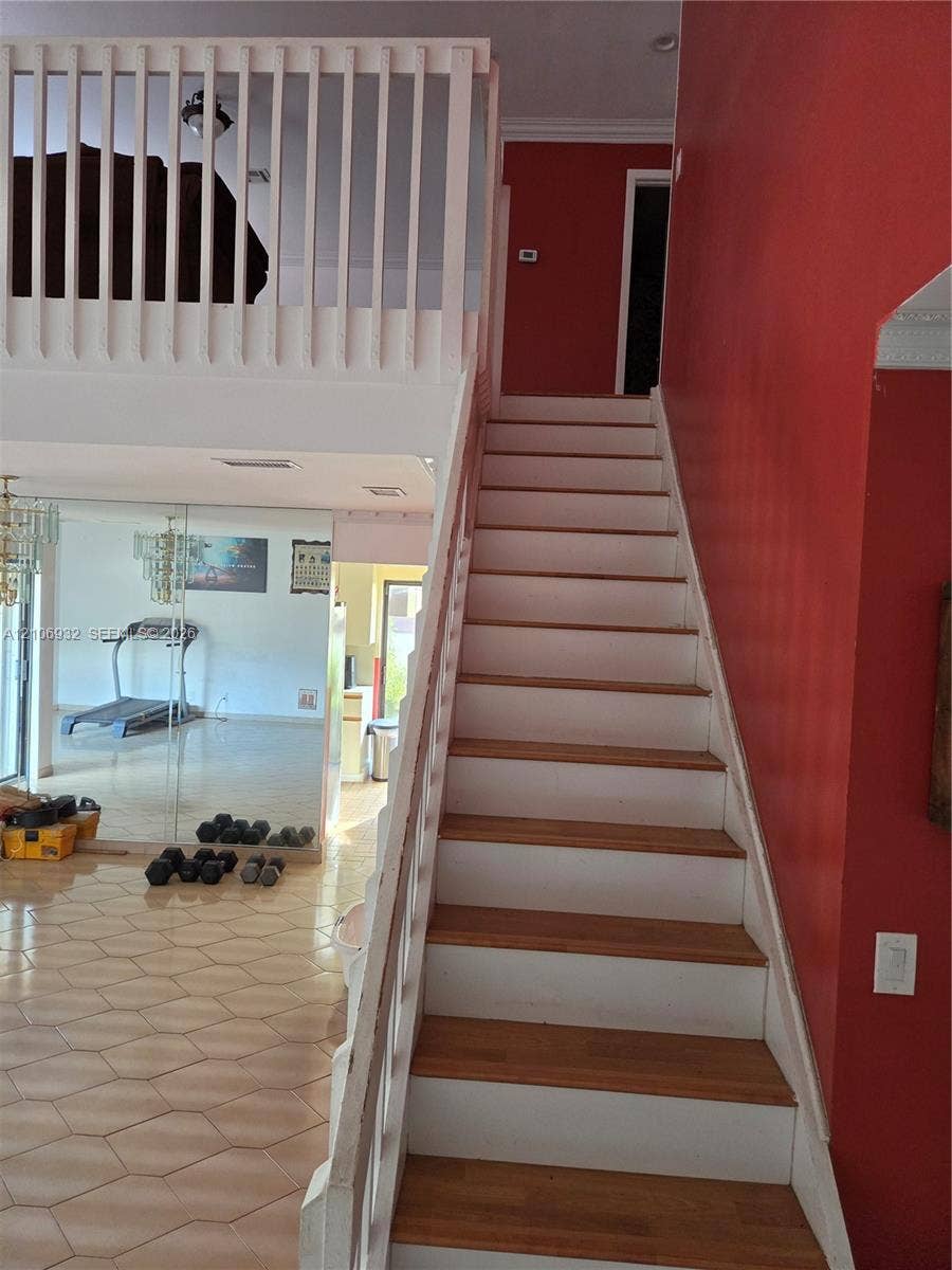 6328 NW 181st Terrace, Hialeah, FL 33015 Staircase featuring wood treads and painted risers, complemented by a white balustrade and mezzanine railing