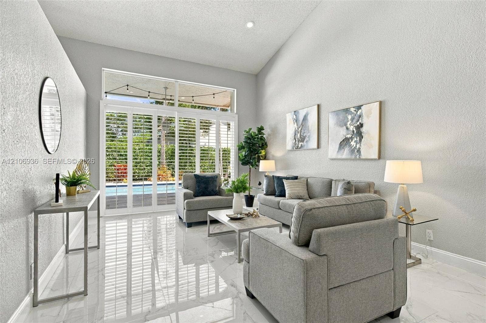 Vaulted ceilings, large-format tile flooring, and floor-to-ceiling glass sliding doors with plantation shutters