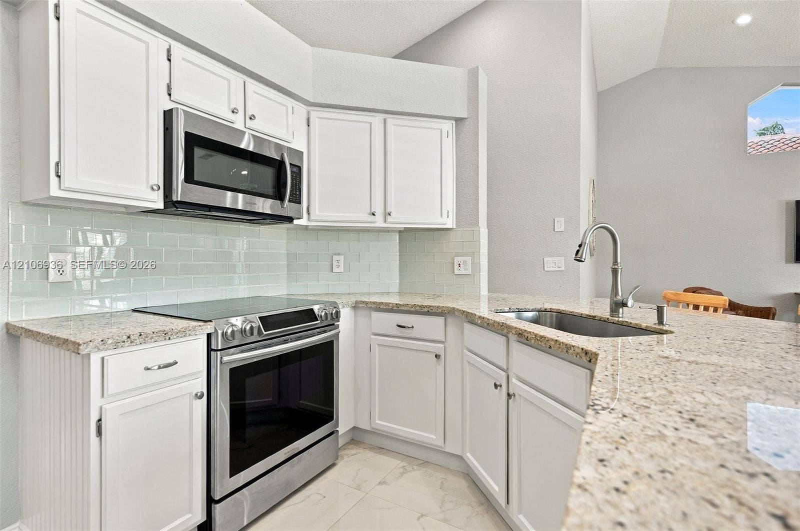 Kitchen featuring white cabinetry, stone-finish countertops, stainless steel appliances, a tile backsplash, and a stainless steel gooseneck faucet
