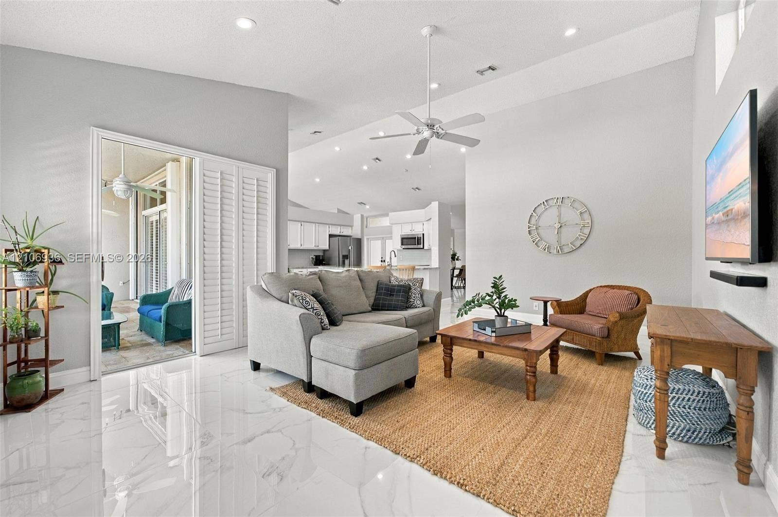 Open-concept interior featuring vaulted ceilings, polished tile flooring, recessed lighting, and white plantation shutters