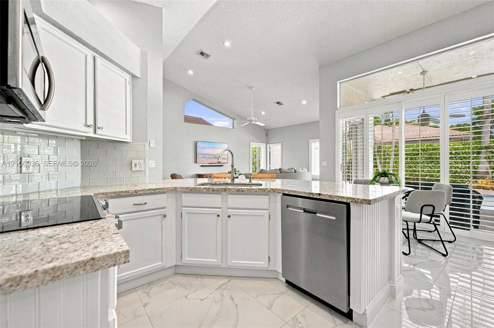 Kitchen featuring white cabinetry, stone-finish countertops, subway tile backsplash, stainless steel dishwasher, and polished tile flooring