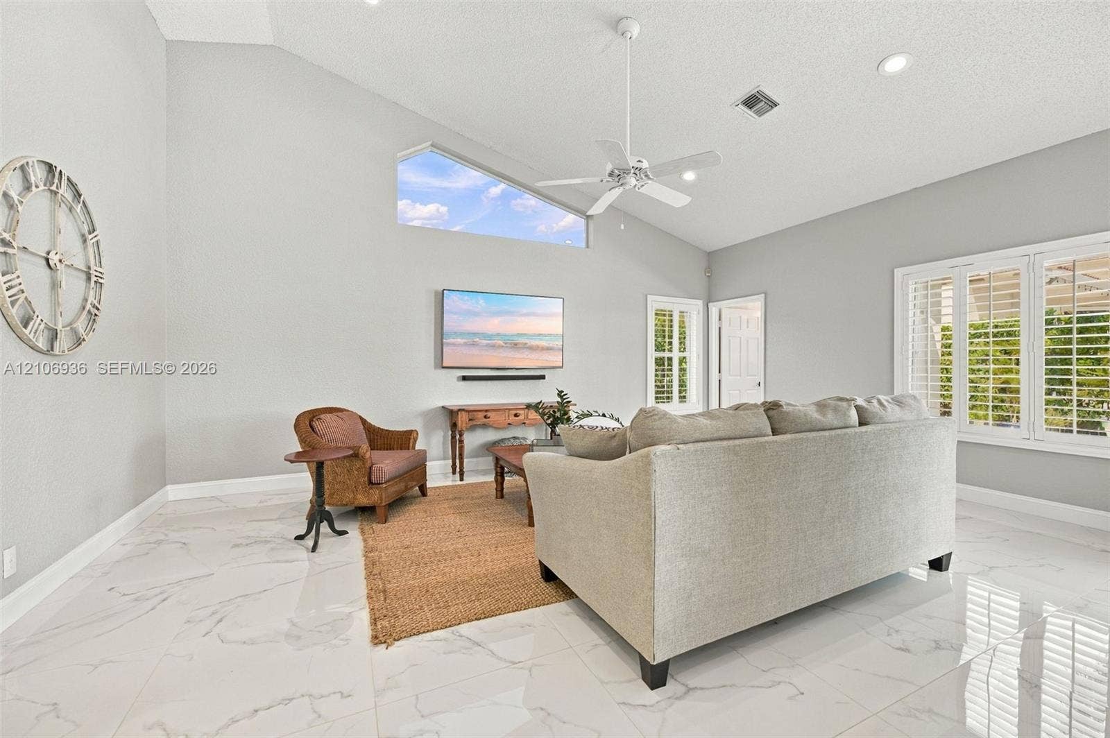 High-vaulted ceilings, polished stone-finish flooring, a contemporary trapezoidal clerestory window, recessed lighting, and interior plantation shutters