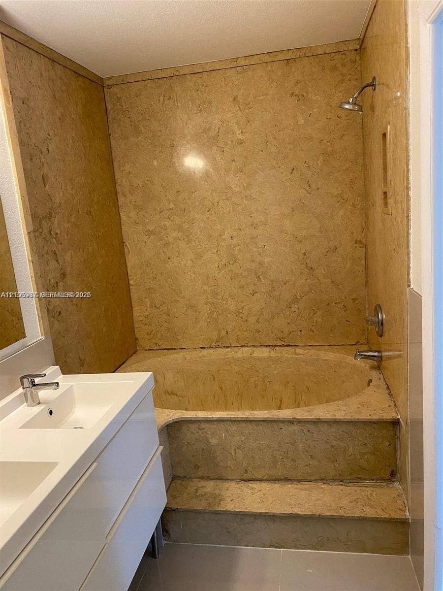 Stone-surround soaking tub with integrated step, modern floating double-sink vanity, and polished metal plumbing fixtures