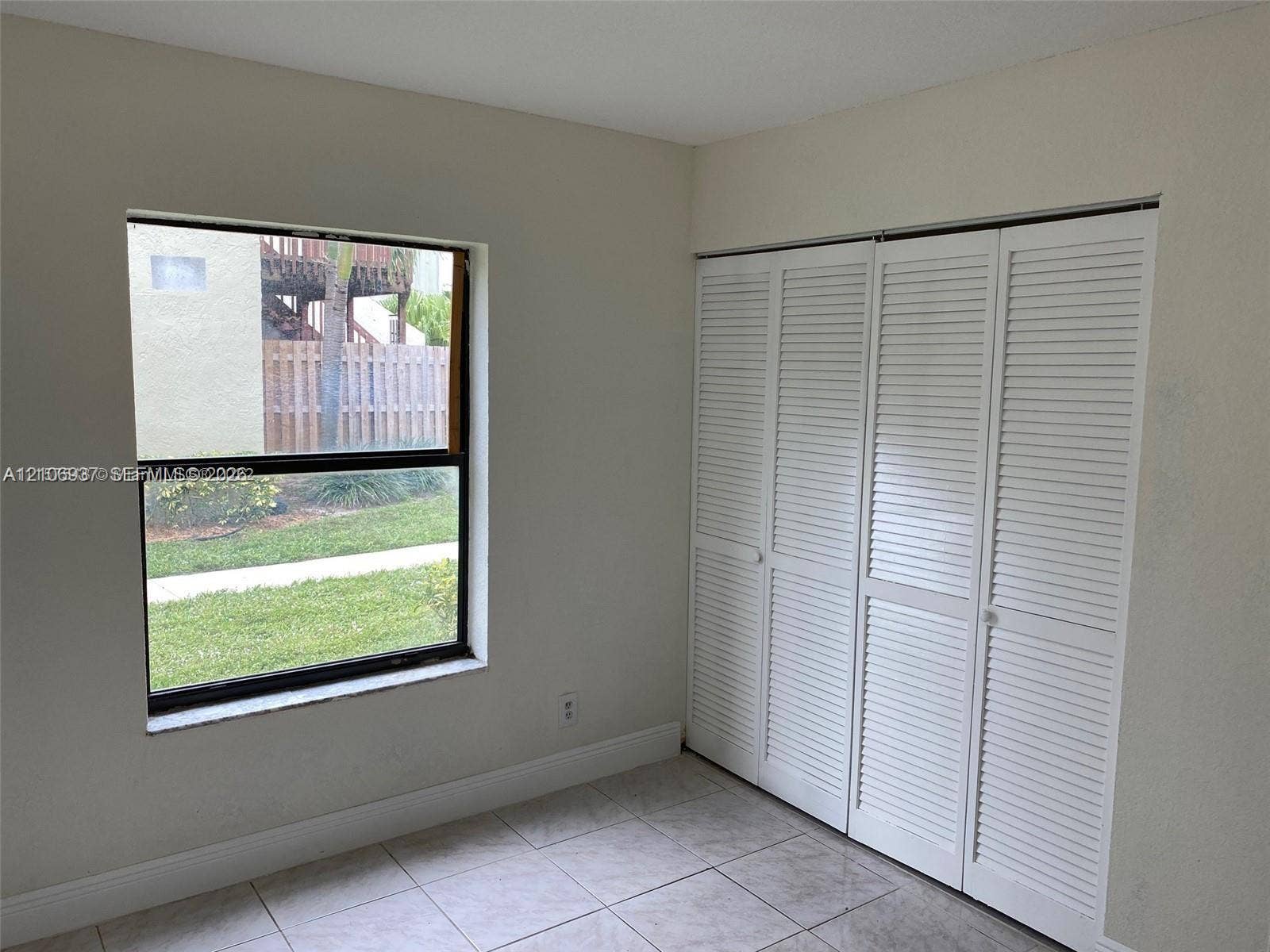 Interior space featuring tile flooring, a window with exterior exposure, and a built-in closet with white louvered bi-fold doors