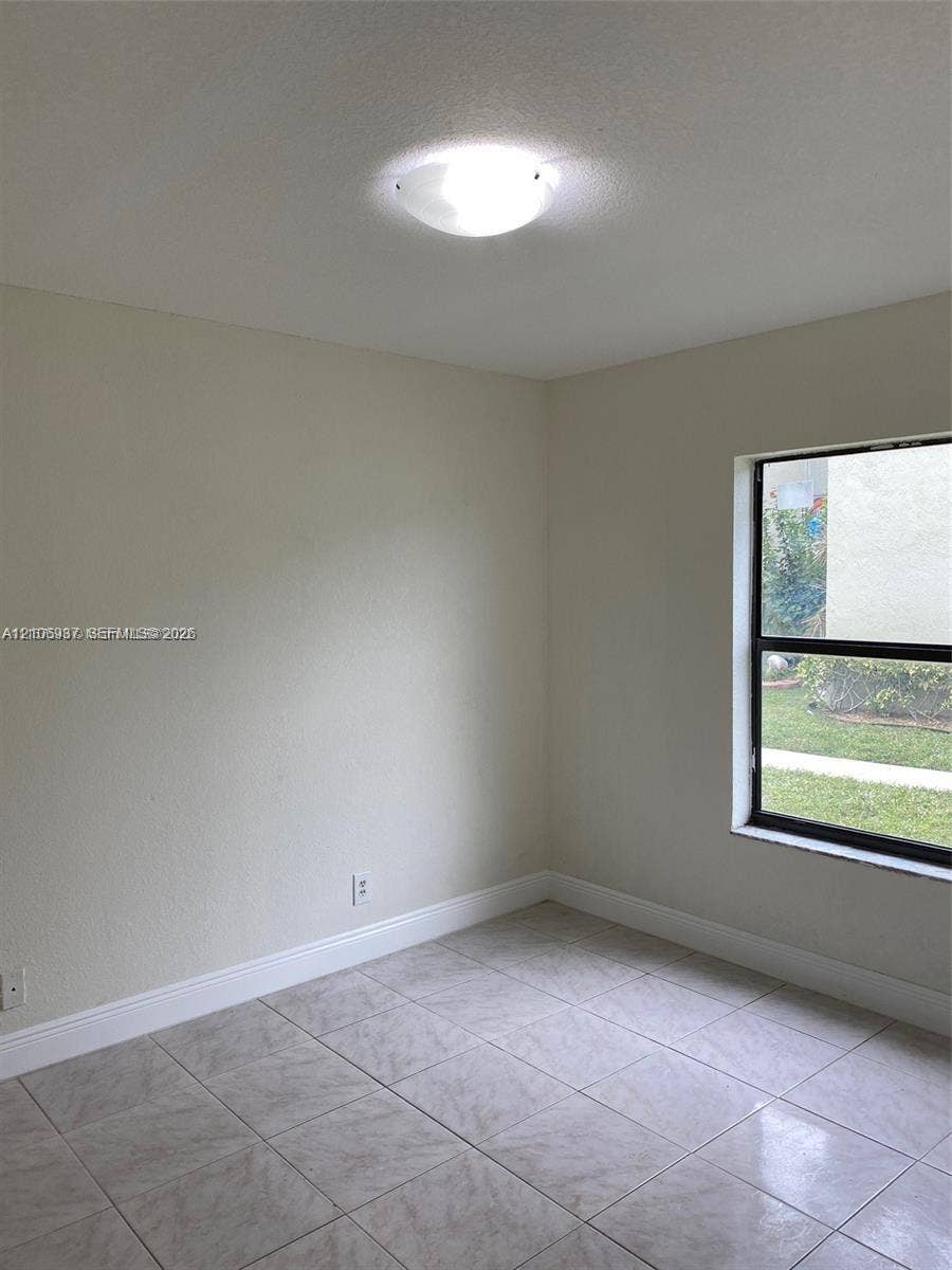 Room featuring tile flooring, neutral wall tones, and a single-pane window with a black frame