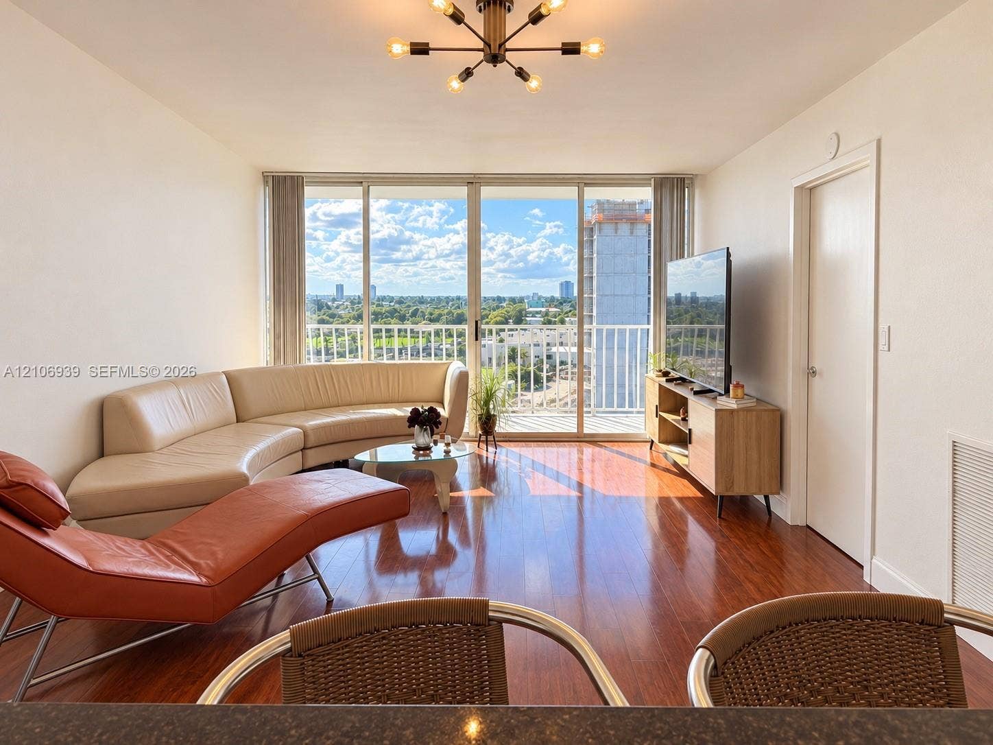 7601 E Treasure Drive, #802, North Bay Village, North Bay Village, FL 33141 Wood-finish flooring, floor-to-ceiling glass sliding doors, private balcony, and multi-arm geometric ceiling fixture