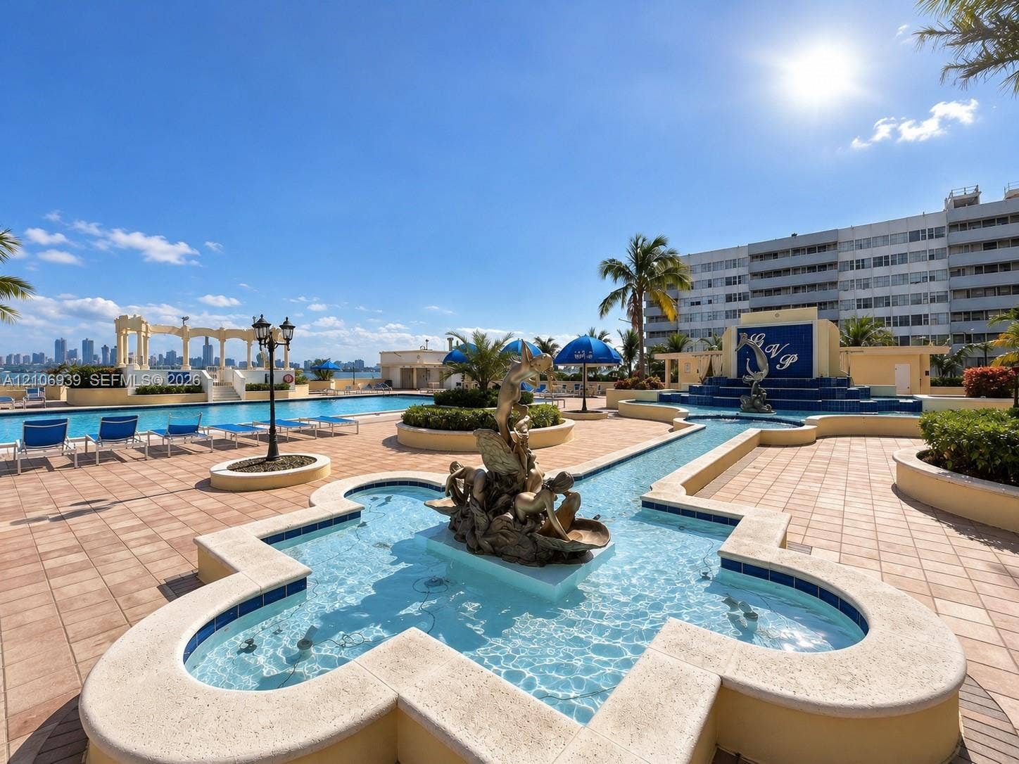 7601 E Treasure Drive, #802, North Bay Village, North Bay Village, FL 33141 In-ground swimming pool with stone-tiled decking, decorative central fountain feature, built-in water feature with tiled backdrop, and stone pergola structure