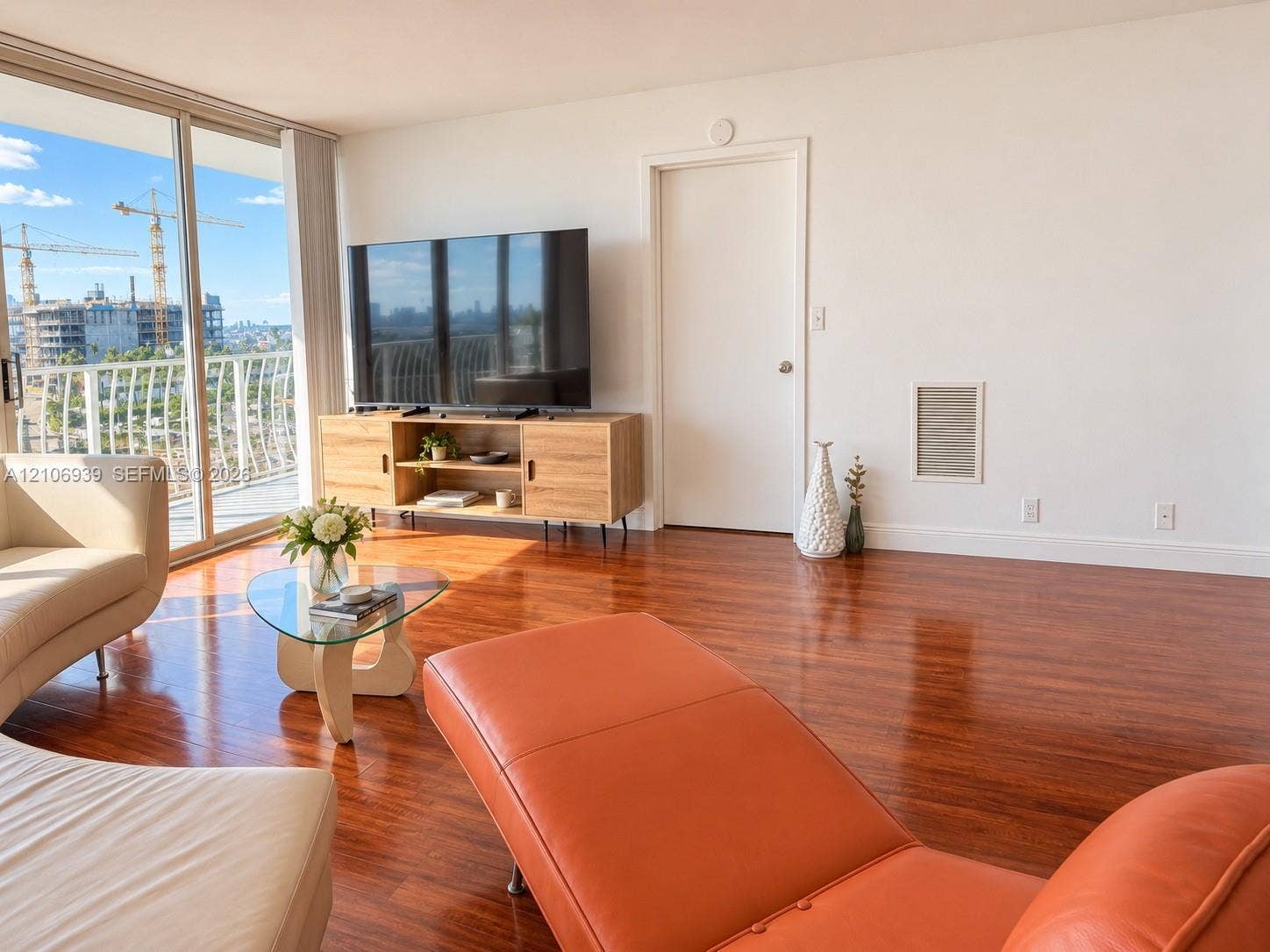 7601 E Treasure Drive, #802, North Bay Village, North Bay Village, FL 33141 Living space featuring full-height glass sliding doors, polished wood-finish flooring, and an exterior metal-railed balcony