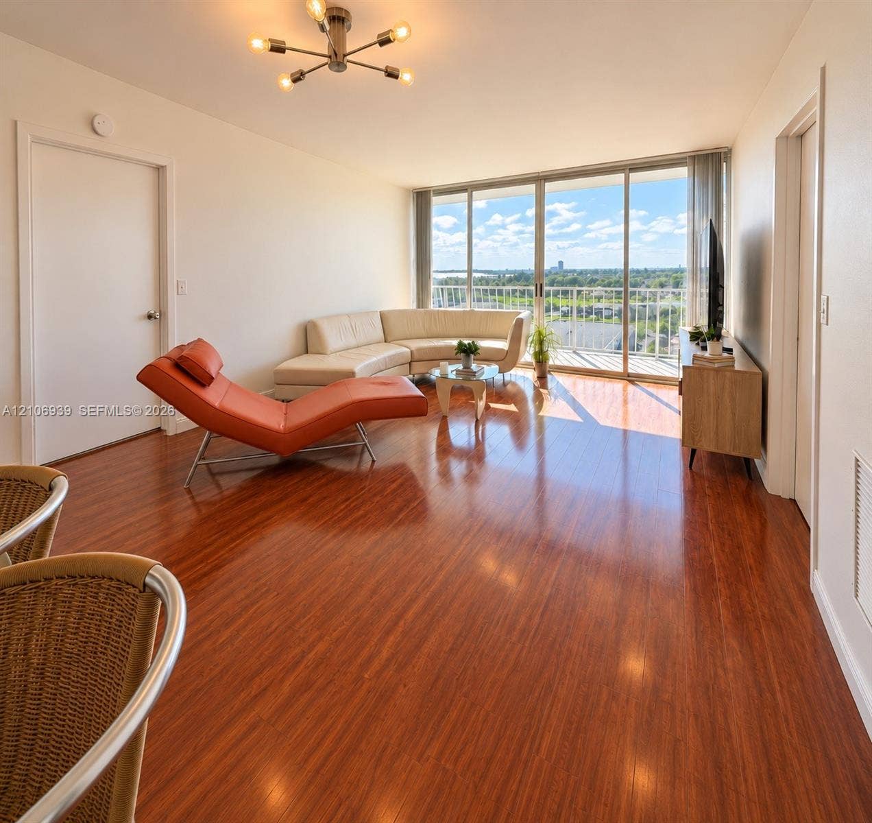 7601 E Treasure Drive, #802, North Bay Village, North Bay Village, FL 33141 Living area featuring wood-finish flooring, floor-to-ceiling sliding glass doors, a balcony, and a multi-arm modern light fixture