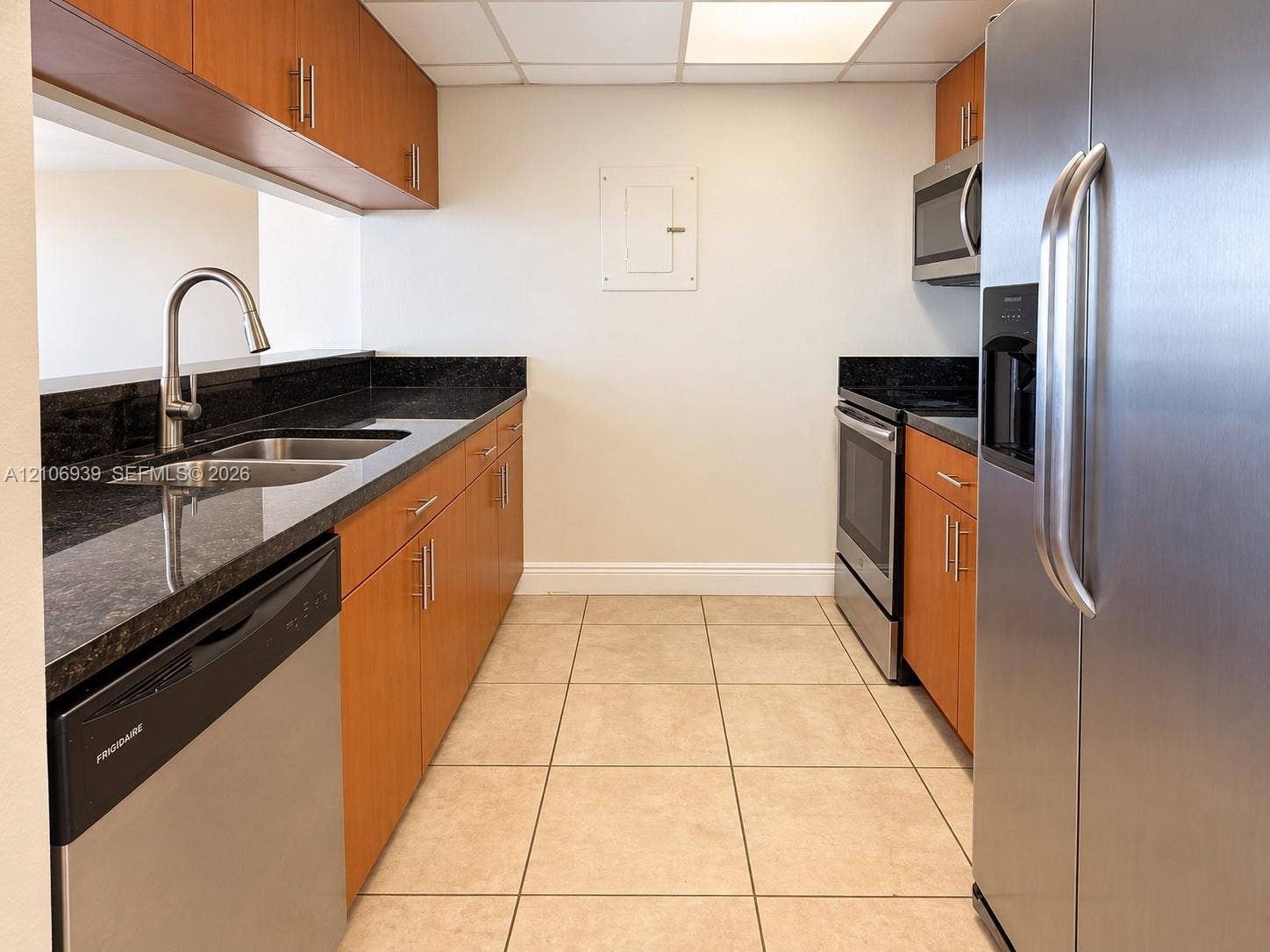 7601 E Treasure Drive, #802, North Bay Village, North Bay Village, FL 33141 Kitchen featuring wood-finish cabinetry, dark stone countertops, stainless steel appliances, ceramic tile flooring, and an undermount dual-basin sink with a pull-down faucet