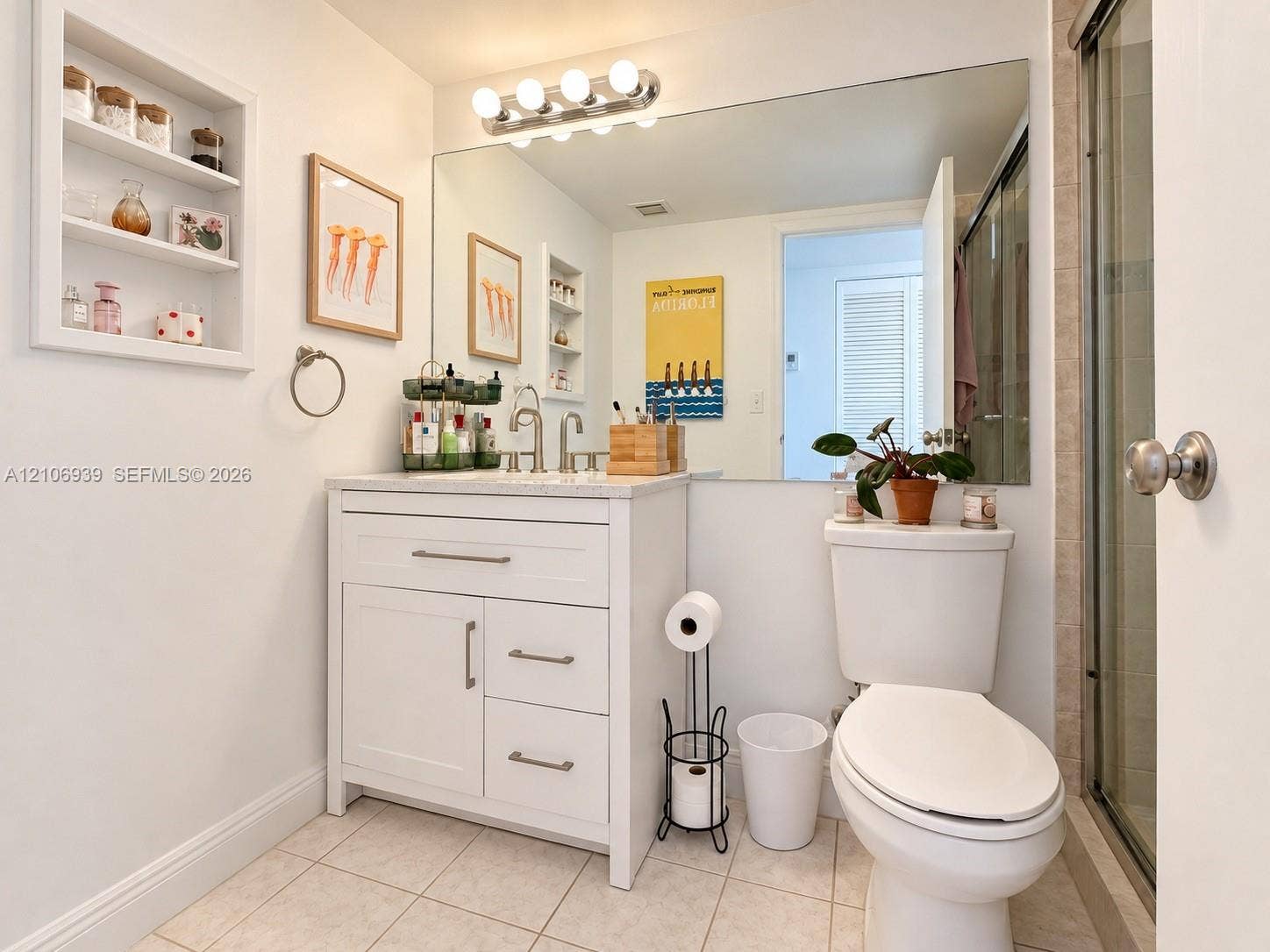 7601 E Treasure Drive, #802, North Bay Village, North Bay Village, FL 33141 Bathroom featuring a vanity with shaker-style cabinetry, light-toned stone countertop, integrated shelving, large-format mirror, and glass-enclosed shower