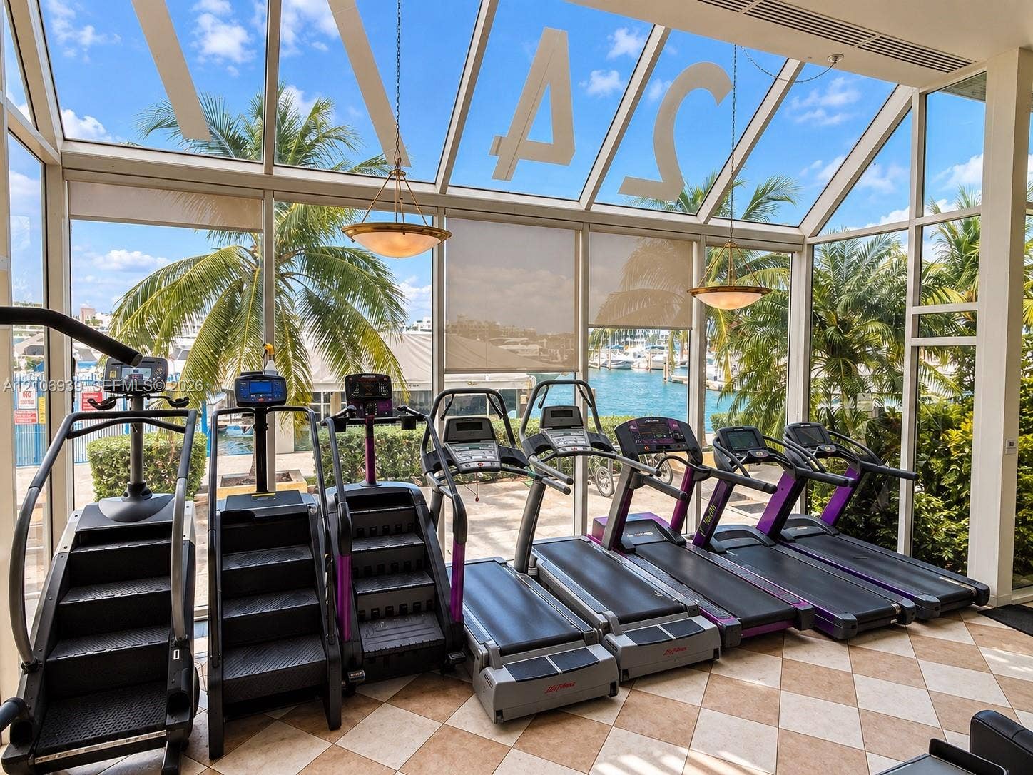 7601 E Treasure Drive, #802, North Bay Village, North Bay Village, FL 33141 Fitness room featuring floor-to-ceiling glass walls, a vaulted glass ceiling, stone tile flooring, and two suspended pendant light fixtures