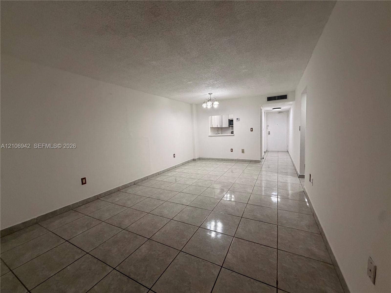 Open interior space featuring light-toned tile flooring, a pass-through window to an additional area, and a ceiling-mounted light fixture