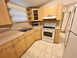 1674 NE 174th Street, #Rear, North Miami Beach, North Miami Beach, FL 33162 Kitchen featuring wood-finish cabinetry, neutral tile flooring, integrated range hood, stainless steel sink, and light-toned countertops