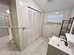 1674 NE 174th Street, #Rear, North Miami Beach, North Miami Beach, FL 33162 Bathroom featuring floor-to-ceiling textured wall tile, white vanity with a rectangular integrated sink, louvered closet doors, and ceramic tile flooring
