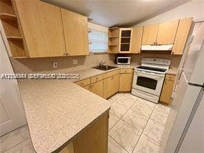 1674 NE 174th Street, #Rear, North Miami Beach, North Miami Beach, FL 33162 Kitchen featuring natural wood-finish cabinetry, light-toned laminate countertops, ceramic tile flooring, and integrated built-in shelving