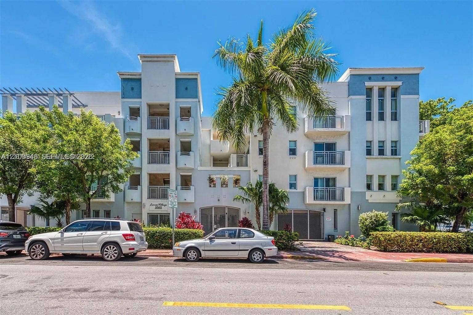 Multi-story building exterior featuring smooth stucco finish, tiered private balconies with metal railings, integrated garage access, and decorative architectural trim