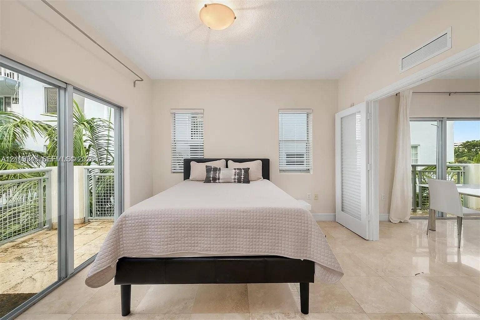 Floor-to-ceiling sliding glass doors, polished stone flooring, dual exterior access points, and recessed ceiling lighting
